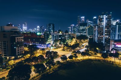 High angle view of illuminated street amidst buildings in city at night