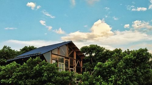 Low angle view of trees and building against sky