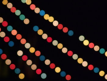 Low angle view of illuminated lighting equipment against black background