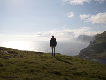 Rear view of man standing on mountain against sky