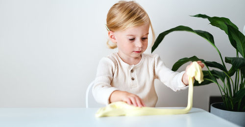 Portrait of cute girl playing with slime at home