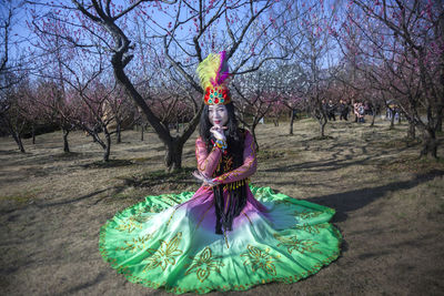 Woman standing by bare tree in park