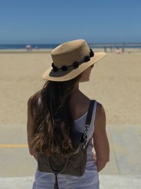 Rear view of woman standing on beach against clear sky