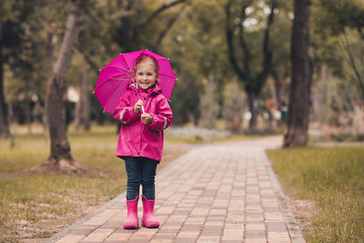 Full length of girl with umbrella standing in park