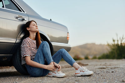 Young woman sitting on car