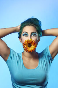 Portrait of woman standing against blue background