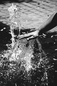 Cropped hand splashing water outdoors