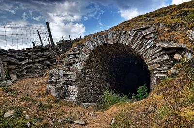 Old ruin amidst field in forest against sky