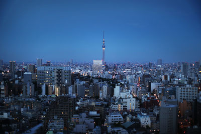 Aerial view of city lit up against blue sky