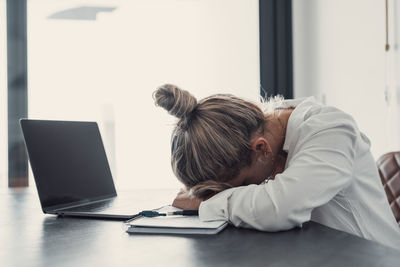 Rear view of woman using laptop at home