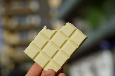 Close-up of hand holding ice cream cone against blurred background