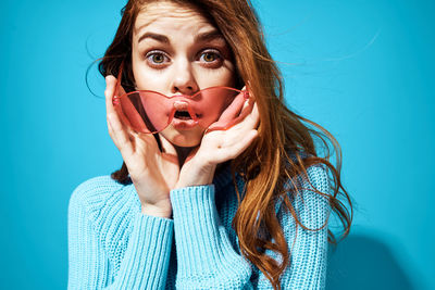 Portrait of young woman against blue background