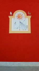 Close-up of clock on red wall