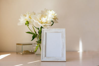Portrait white picture frame mockup on wooden table.
