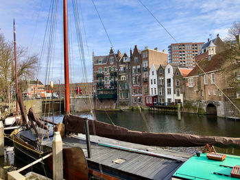 Boats moored at harbor by buildings in city against sky