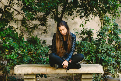 Woman with eyes closed sitting on seat against plants