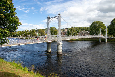 Bridge over river against cloudy sky