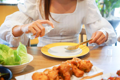 Girl spray alcohol food, pharma grade on dish, spoon and fork before using to cleaning and disinfect