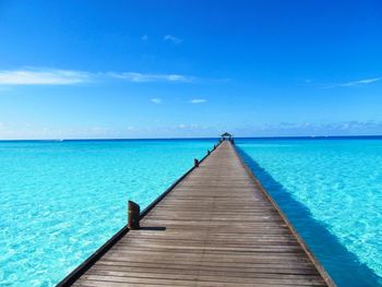 Pier over sea against blue sky