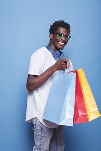 Portrait of young woman holding gift against blue background