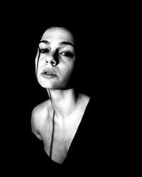 Close-up portrait of a young woman over black background