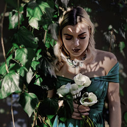 Portrait of young woman standing by plants