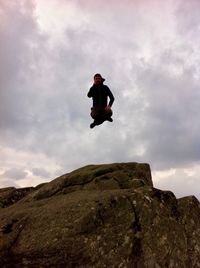 Low angle view of man paragliding on rock against sky