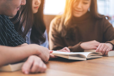 Midsection of woman reading book on table