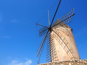 Low angle view of traditional windmill against blue sky