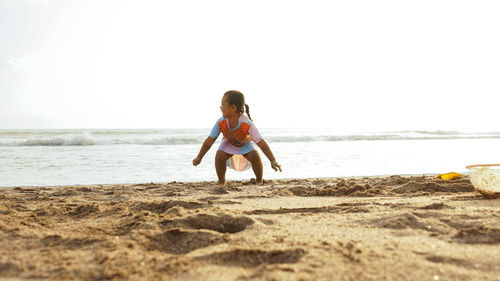 Full length of girl on beach against clear sky