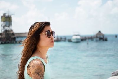 Young woman wearing sunglasses by sea against sky