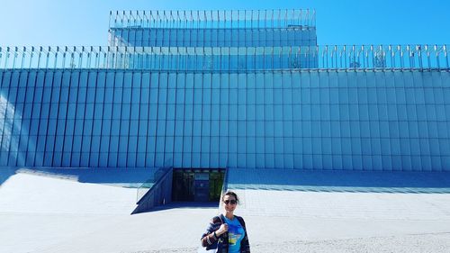 Portrait of woman standing against building