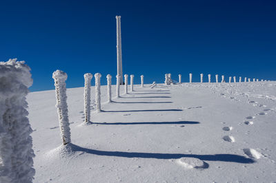 Snow covered landscape against clear blue sky