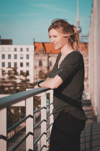 Woman standing by railing against sky