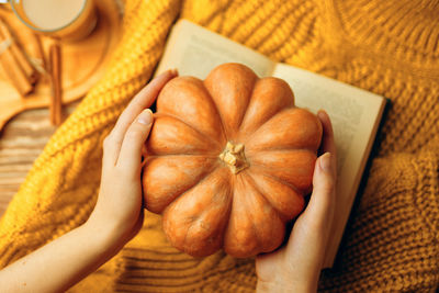 Midsection of person holding pumpkin on table