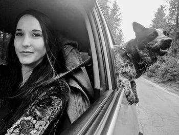 Portrait of woman with dog in car
