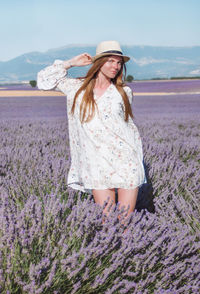 Young long hair woman in hat and dress among lavender fields in provence, france.