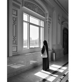 Rear view of woman standing by window in building