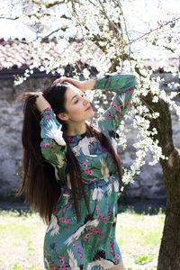 Full length of woman standing against tree