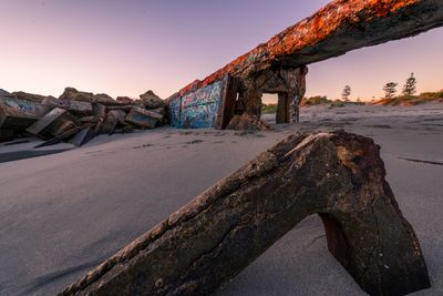 Damaged car against clear sky during sunset