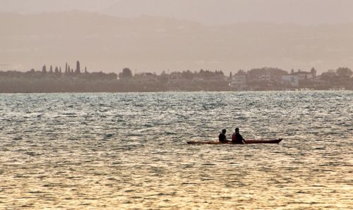 Men sitting on boat in sea against sky