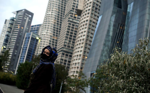 Low angle view of woman standing against modern buildings