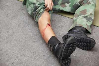 Low section of army soldier with injury on road