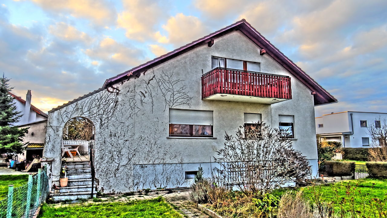 EXTERIOR OF OLD BUILDING BY HOUSE AGAINST SKY