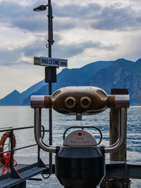 View of coin-operated binoculars by sea against sky