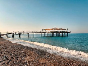 Pier on beach against clear sky