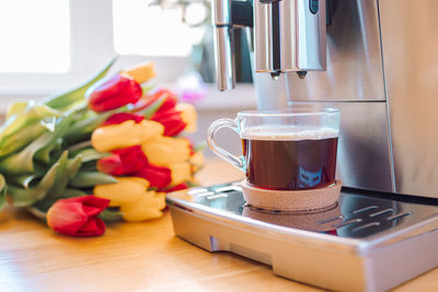 Cup of coffee with milk and tulips flowers on wooden kitchen table. freshly brewed cappuccino 