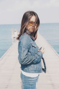 Young woman standing at beach against sky