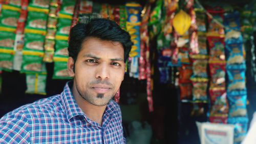 Close-up portrait of young man against store