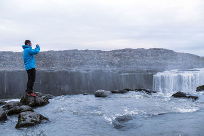 Man standing on rock against sky